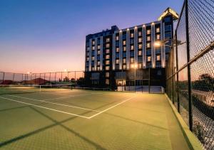 a tennis court with a building in the background at Kinno International Hotel in Tema