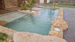 a large pool with rocks in a backyard at Villa Loma de Bas 1 y 2 in Águilas