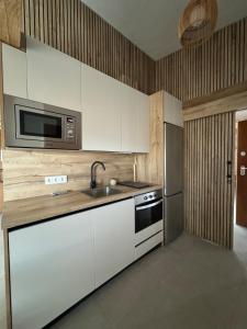 a kitchen with white cabinets and a sink and a microwave at Villa Loma de Bas 1 y 2 in Águilas +12 photos