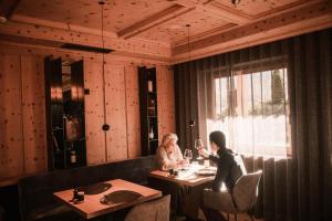 due persone sedute a un tavolo in un ristorante di Hotel Christof a Monguelfo Altre 39 foto