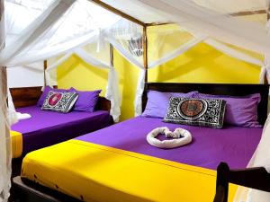 two beds in a tent with purple and yellow at Mango Villa - Panama Near Arugam Bay in Panama