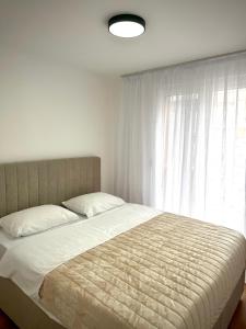 a bed in a bedroom with a large window at Apartman 307 in Lukavica