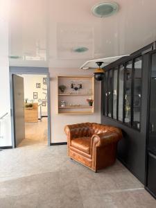 a brown leather chair in a living room at Logis Hôtel de Paris - Restaurant - Pâtisserie in Saint-Avold