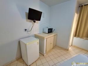 a small kitchen with a television and a refrigerator at Flats CTC Araras in Caldas Novas