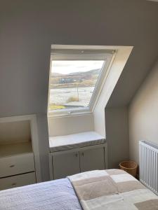 a bedroom with a window with a bed in front of it at Skyefall Apartment in Uig