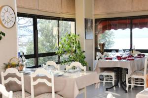 a dining room with white tables and chairs and a clock at Teras Motel 12 Adults Only in Foça