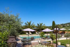 a pool with tables and chairs and umbrellas at Hôtel Les Lentisques in Cargèse