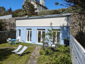 a white house with chairs in a yard at Penuel Tiny House in Granville
