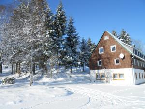 a barn in a snow covered field with trees at Pension Haus Pentacon in Kurort Altenberg