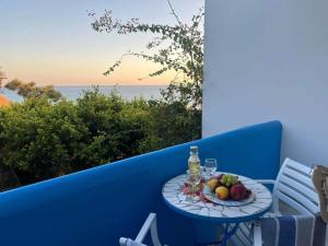 a table with a plate of fruit and wine glasses at Panorama Melina Apartments in Kastrí