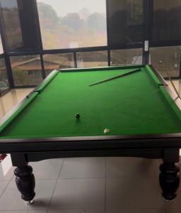 a green pool table in front of a window at The Sixth Abode Farms 5 BHK Villa with Swimming Pool, Turf, Lawn & Indoor Games- Khopoli in Jambhulpāda