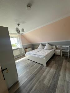 a bedroom with a white bed and wooden floors at Ferienwohnung Wildblume in Fehmarn