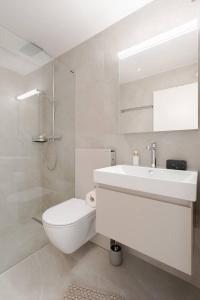 a white bathroom with a toilet and a sink at Summit View Apartment in Spiez +60 photos