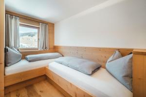 two beds in a room with a window at Kuenzerhof Apartments in Braies