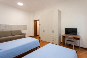 a bedroom with two beds and a desk with a television at Residenza Santa Rita in Novara