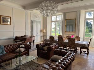 a living room with leather furniture and a piano at Château de Mauhic - 15th century in Loubédat +75 photos