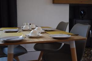 a wooden table with plates and utensils on it at Woodlyn Guest House in Gatehouse of Fleet +18 photos