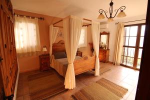 a bedroom with a canopy bed with curtains at Loma la Parra in Valle de Abdalagís +33 photos