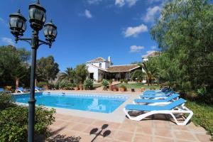 a row of lounge chairs next to a swimming pool at Loma la Parra in Valle de Abdalagís