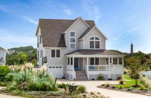 a white house with a lighthouse in the background at Puppy Love - Corolla, Villages at Ocean Hill, Pool, Hot Tub, Nearby Amenities, Lighthouse, Pets OK in Corolla