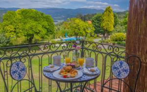 a table with a plate of food on a balcony at Solar Alegria Lodge in Oliveira de Frades