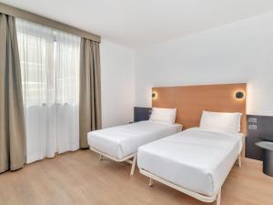a hospital room with two beds and a window at B&B HOTEL Milano Cologno Studios in Cologno Monzese