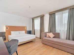 a hotel room with a bed and a couch at B&B HOTEL Milano Cologno Studios in Cologno Monzese
