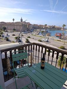 a green table with a bottle of wine on a balcony at L'Aragosta Guesthouse in Alghero