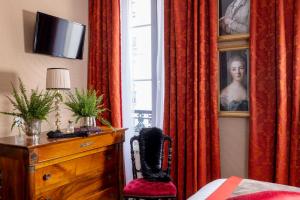 a bedroom with a dresser and a window with red curtains at Hotel De Seine in Paris