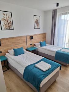two beds in a hotel room with blue pillows at VILLA 17 Noclegi in Płock