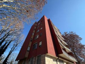 a tall red building with trees in the background at RETLAV LUXURY Apartment in San Donato Milanese