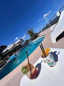 two drinks on a table next to a swimming pool at ERNESTINA VILLAGE Resort Apart & suites in Villa Carlos Paz +46 photos