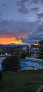 a large swimming pool with a sunset in the background at ERNESTINA VILLAGE Resort Apart & suites in Villa Carlos Paz