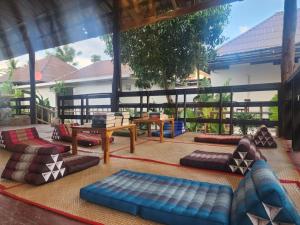 a patio with several couches and tables on a patio at Lazy Garden Hostel in Phra Ae beach