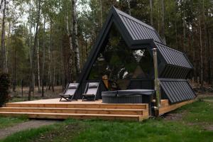 a black roofed house with two chairs on a deck at Mandra Petrichor in Zabuyanʼye