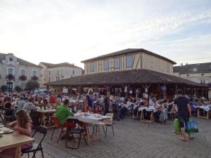 a group of people sitting at tables in a courtyard at Duplex pour 2-4 personnes à Monflanquin - Piscine - Terrasse - Parking - Campagne - Lot-et-Garonne - draps inclus in Monflanquin