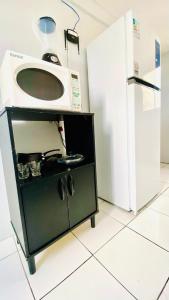a microwave in a kitchen next to a refrigerator at Ap com ar próximo ao centro in Crateús +6 photos