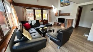 a living room with a leather couch and chairs at Chalet Sunstar in Saas-Grund