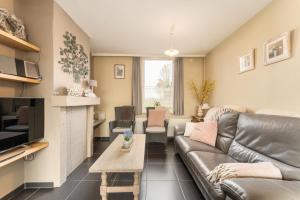 a living room with a leather couch and a table at Het Rustplekje in Alveringem
