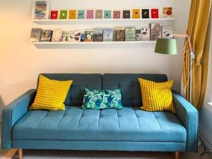 a blue couch with yellow pillows in a living room at Bittern Lodge in Cromer