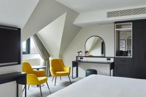 a hotel room with a bed and chairs and a desk at Leonardo Hotel Dublin Christchurch in Dublin