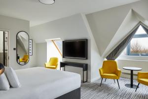 a hotel room with a bed and chairs and a tv at Leonardo Hotel Dublin Christchurch in Dublin