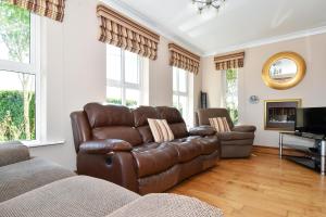 a living room with a leather couch and a television at Mannin Lodge in Ballyconneely