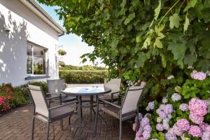 a patio with a table and chairs and flowers at Mannin Lodge in Ballyconneely