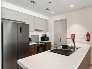 a kitchen with white cabinets and a stainless steel refrigerator at Exquisite 2BDR Retreat In Forte-33 in Dubai