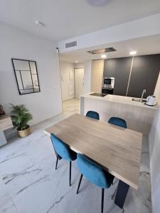 a kitchen with a wooden table and blue chairs at Playa Flamenca modern groundfloor apartment with pool access in Orihuela Costa