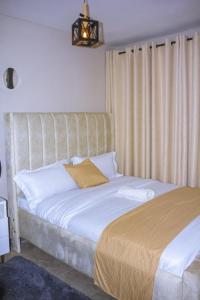 a bedroom with a large bed with white sheets at TanuStays - Modern 1 Bedroom at Royal Suburbs Tsavo, near TRM in Nairobi