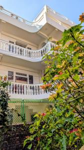 a white house with a balcony and some trees at Tuyu Chhye in Kathmandu