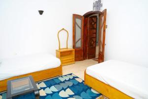 a room with two beds and a door at Aisha Guest House And Restaurant in Al Aqālitah