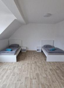 two beds in a room with a wooden floor at Privatpension Dreger in Alzey
